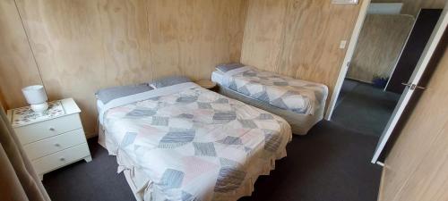 a small room with two beds and a night stand at Tongariro Estate in National Park