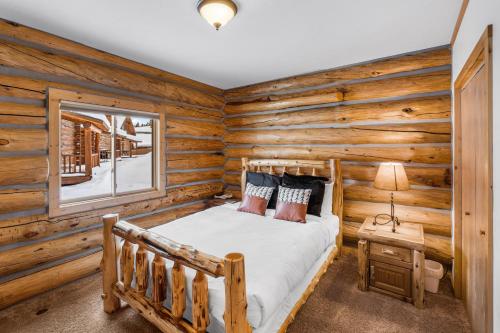 a log cabin bedroom with a bed and a window at King's Cabin in West Yellowstone