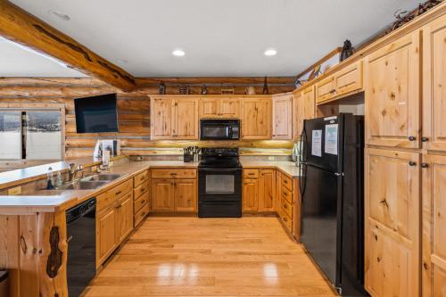a kitchen with wooden cabinets and a black refrigerator at King's Cabin in West Yellowstone