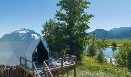 a person standing in a dome tent next to a river at Tammah Jackson Hole in Wilson