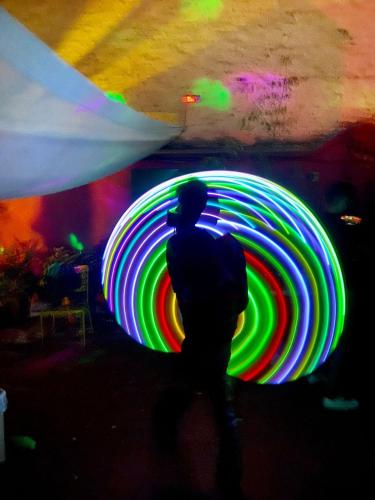 a man is standing in front of a large neon wheel at Free Spirit Hostel Guadalajara in Guadalajara
