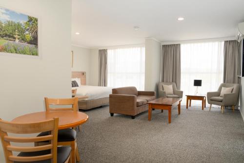 Habitación de hotel con cama, mesa y sillas en Posthouse Motor Lodge, en Goulburn