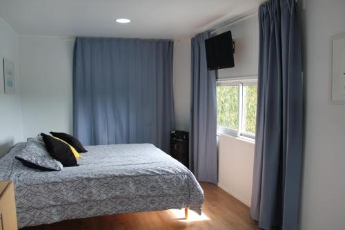 1 dormitorio con 1 cama con cortinas azules y ventana en Cabaña con fogon y tinaja en plena naturaleza! en Algarrobo