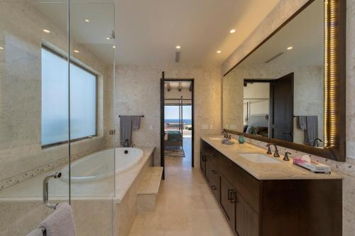 a bathroom with a tub and a large mirror at Seaside Serenity A Luxurious Coronado Home in Cabo San Lucas