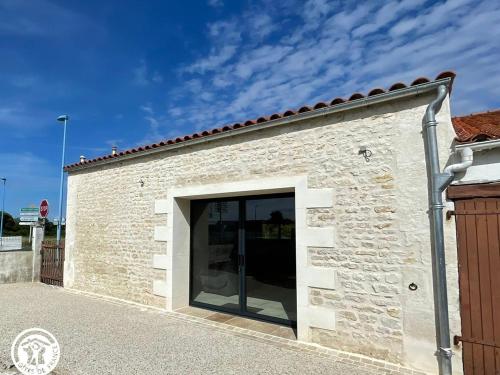 a white brick building with a large glass door at Maison confortable 6 pers. - 20km de La Faute sur Mer - 67km Puy du Fou - Terrasse et Proximité Routes - FR-1-426-534 in Les Magnils-Reigniers