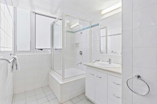 a white bathroom with a shower and a sink at Ambassador Beachfront Apartments - Hosted by Burleigh Letting in Gold Coast