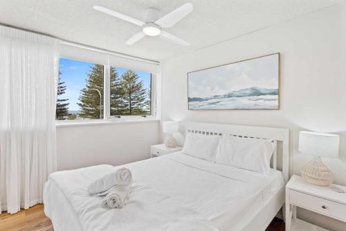 a white bedroom with a bed and a window at Ambassador Beachfront Apartments - Hosted by Burleigh Letting in Gold Coast