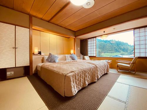 a bedroom with a large bed and a large window at Hotel Kameya in Osaki