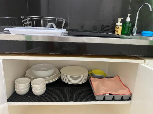 a kitchen shelf with plates and bowls and a sink at 1-BR spacious lofted apartment near BGC Taguig City (THR105) in Manila