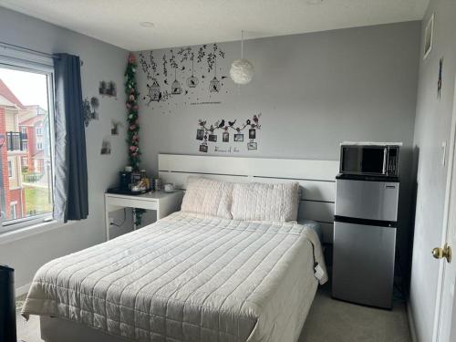 ein kleines Schlafzimmer mit einem Bett und einer Mikrowelle in der Unterkunft Private, Secure, Immaculate & Cozy Room in Brampton