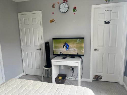 ein Schlafzimmer mit einem TV und einem Schreibtisch mit einem TV und einer Uhr in der Unterkunft Private, Secure, Immaculate & Cozy Room in Brampton