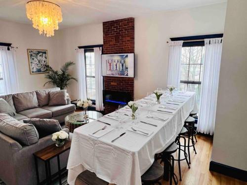 ein Wohnzimmer mit einem langen Tisch und einem weißen Tischtuch in der Unterkunft Host your group - West End Sea Captain Home in Portland