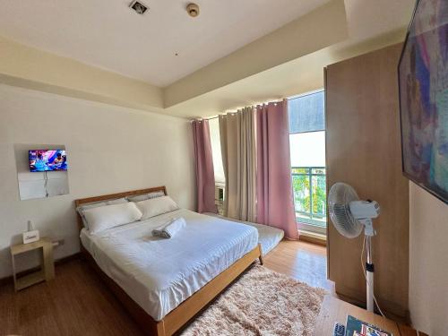Schlafzimmer mit einem Bett und einem Fenster mit einem Ventilator in der Unterkunft Stayover at Azure in Manila