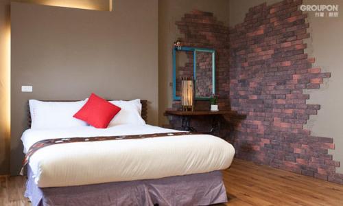 a bedroom with a large bed with a brick wall at 艾希兒民宿 I'm Here hostel l小家庭包棟首選l 台東包棟 l台東火車站l背包單人 in Taitung City