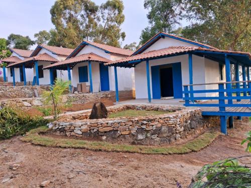 une rangée de maisons bleues et blanches avec un banc bleu dans l'établissement Pousada Fazendinha Alto da Serra, à Serra Negra