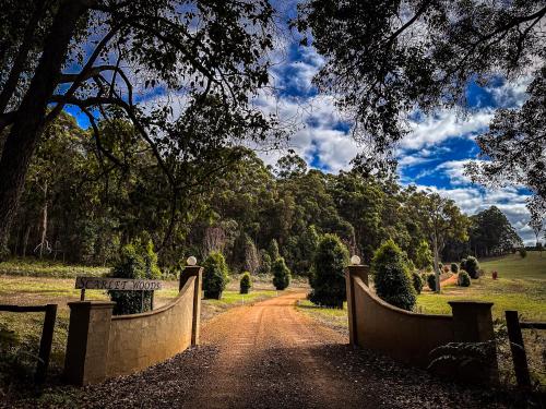 a dirt road with a bridge in a field at Scarlet Woods Chalets in Quinninup