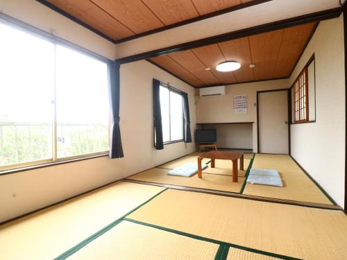 an empty room with a table and windows at 民宿かず in Sosa