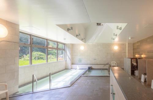 a large bathroom with a swimming pool and a window at Nayoro Onsen Sunpillar in Nayoro