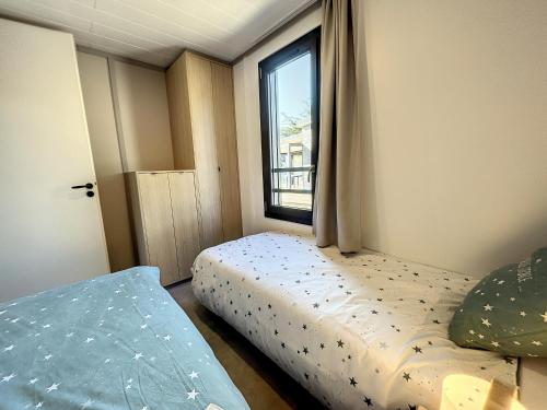 une petite chambre avec un lit et une fenêtre dans l'établissement Chalet Jullouville - 6 pers. - Piscine chauffée - Terrasse privative - Proche plage et commerces - FR-1-361-470, à Jullouville