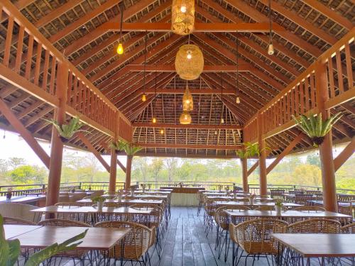 a restaurant with tables and chairs and a wooden ceiling at Kebun Teh Wonosari Rollaas Hotel & Resort in Malang