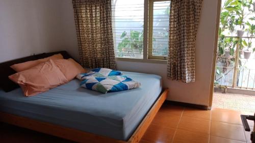 a bedroom with a bed with pillows and a window at Petik Merah Homestay in Yogyakarta