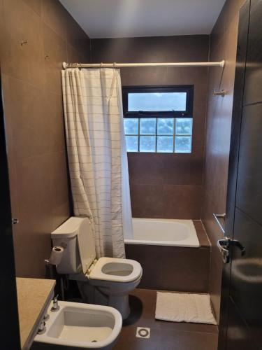 a bathroom with a toilet and a tub and a sink at Duplex Familiar in Yerba Buena