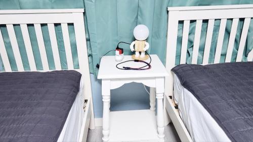 a white table with a lamp on it next to two beds at The house of gallery in Daegu