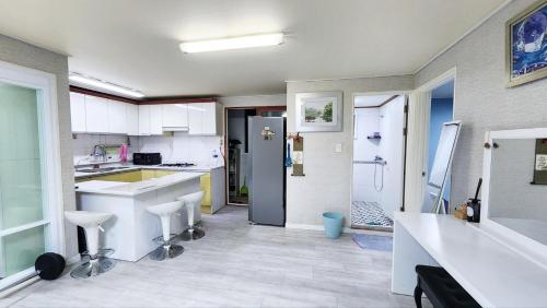 a kitchen with white counters and a sink and a refrigerator at The house of gallery in Daegu