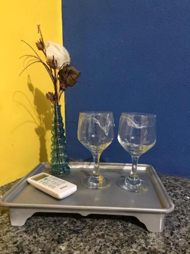 a tray with three wine glasses and a cell phone at Chalé recanto do sol in Santo Amaro