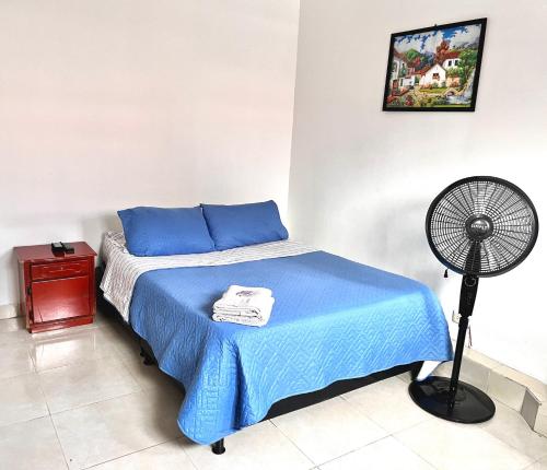 um quarto com uma cama azul e uma ventoinha em Apartaestudio Centro Pereira em Pereira