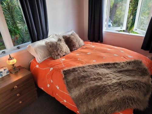 Un dormitorio con una cama naranja con una manta peluda en City Retreat, en Whangarei
