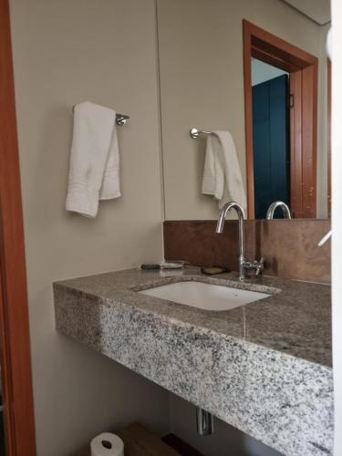eine Badezimmertheke mit einem Waschbecken und einem Spiegel in der Unterkunft Quinta de Santa Bárbara Eco Resort Luxo Reveillon in Pirenópolis