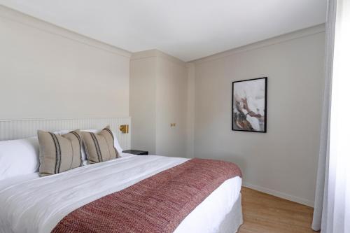 Motel Caloundra في كالوندرا: غرفة نوم بيضاء مع سرير كبير مع بطانية حمراء