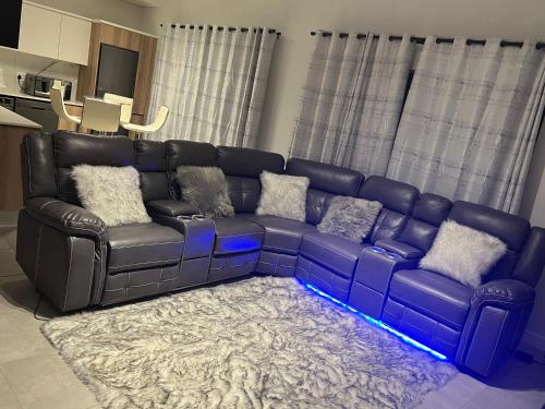 sala de estar con sofá de cuero negro con luces azules en Munyaka Lagoon Penthouse en Midrand