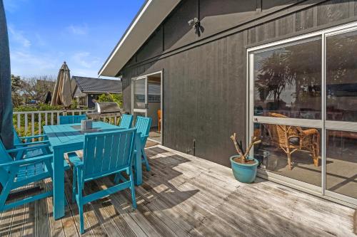 a patio with blue chairs and a table on a deck at Coastal Oasis - Papamoa Beach Holiday Home in Papamoa