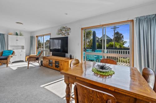 a living room with a dining table and a television at Coastal Oasis - Papamoa Beach Holiday Home in Papamoa