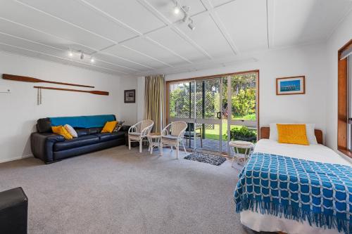 a bedroom with a bed and a couch and a table at Coastal Oasis - Papamoa Beach Holiday Home in Papamoa