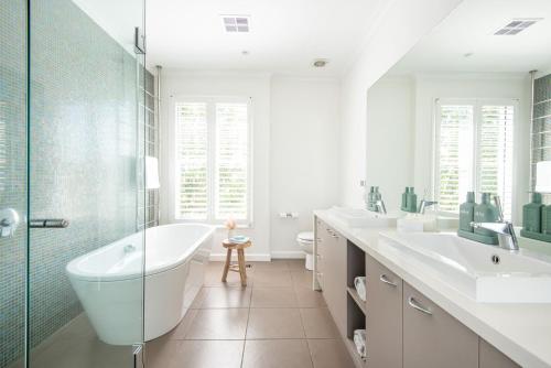 a bathroom with a tub and two sinks and a shower at Hampton Haven Pool metres to the Beach in Melbourne