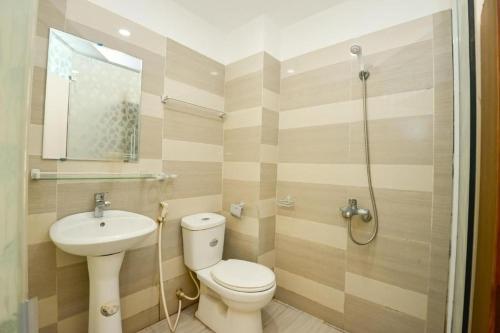 La salle de bains est pourvue de toilettes et d'un lavabo. dans l'établissement Hà Nội Vàng Hotel - Ngõ 4 Phương Mai - by Bay Luxury, à Hanoï