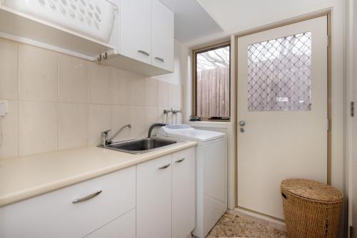 a white kitchen with a sink and a window at Somerset Sanctuary in Safety Beach in Safety Beach