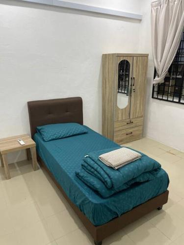 a bedroom with a bed with blue sheets and a table at SunShine HomeStay in Bukit Mertajam