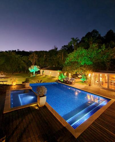 a swimming pool in a backyard at night at Pousada Boutique Itaipava in Itaipava