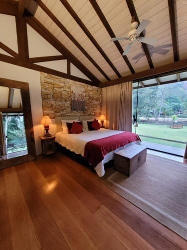 a bedroom with a large bed and a large window at Pousada Boutique Itaipava in Itaipava