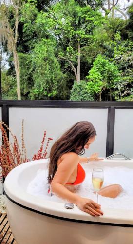 a woman in a bathtub with a glass of wine at Pousada Boutique Itaipava in Itaipava
