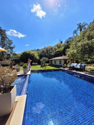a woman is standing next to a swimming pool at Pousada Boutique Itaipava in Itaipava