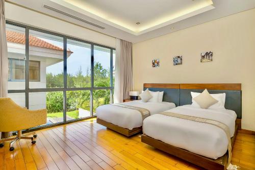 Un dormitorio con dos camas y una gran ventana. en Danang Amazing Ocean Villas, en Da Nang