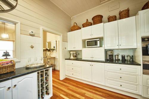 a kitchen with white cabinets and black counter tops at Inglenook Cottage Healesville in Healesville