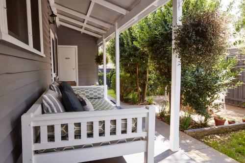 a white bench on the porch of a house at Inglenook Cottage Healesville in Healesville