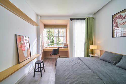 um quarto com uma cama, uma secretária e uma janela em M Village CMT8 em Ho Chi Minh