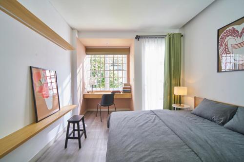 a bedroom with a bed and a desk and a window at M Village Living Cách Mạng Tháng 8 in Ho Chi Minh City